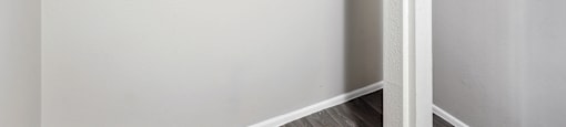 an empty closet in a home with white walls and wood floors